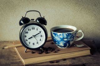 Tasse d'espresso posée sur le comptoir à côté d'une horloge murale
