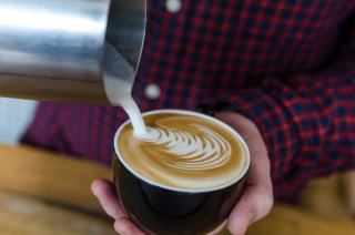 Café versé lentement sur un lait d'avoine dans un verre posé au comptoir