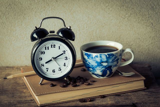 Doser sa caféine et choisir son heure de dernière tasse Tasse d'espresso posée sur le comptoir à côté d'une horloge murale